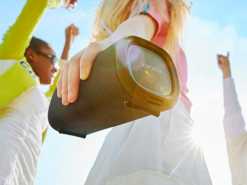 Personen tanzen mit einer Bluetooth-Box in der Hand.