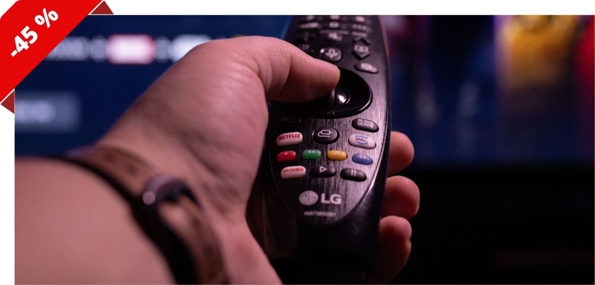 Person hält eine LG-Fernbedienung in Richtung eines Fernsehers.