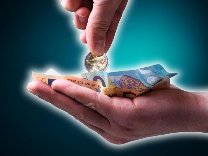 Person hält eine Hand auf, in der Geld liegt