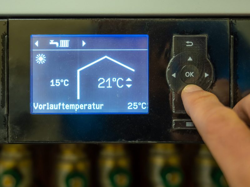 Person stellt die Vorlauftemperatur bei der Heizung ein.