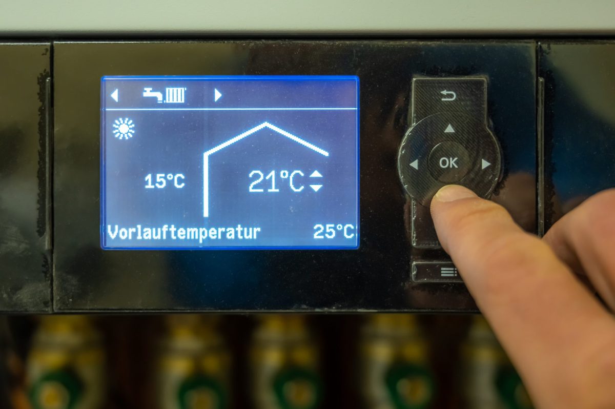 Person stellt die Vorlauftemperatur bei der Heizung ein.