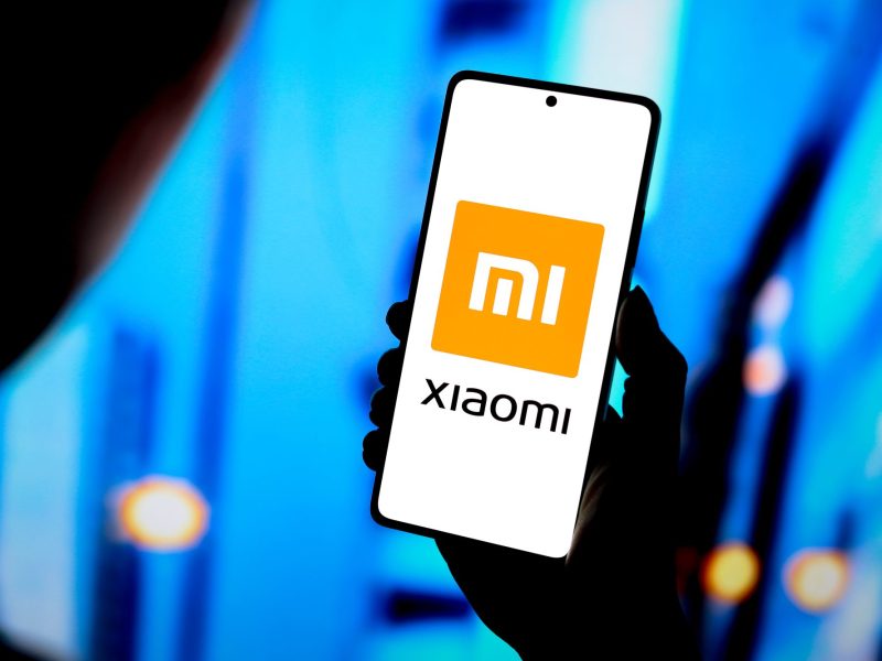 Person hält ein Smartphone in der Hand, auf dem Display ist das Xiaomi-Logo.