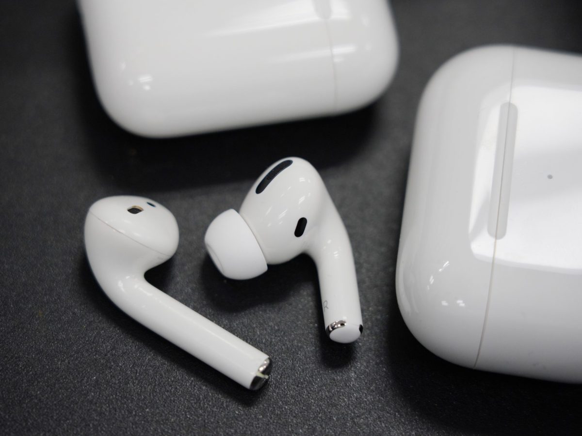 AirPods neben Lade-Case auf schwarzem Untergrund.