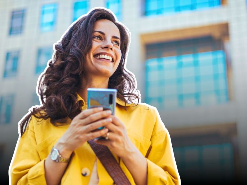 Lächelnde Frau mit Smartphone in ihrer Hand.