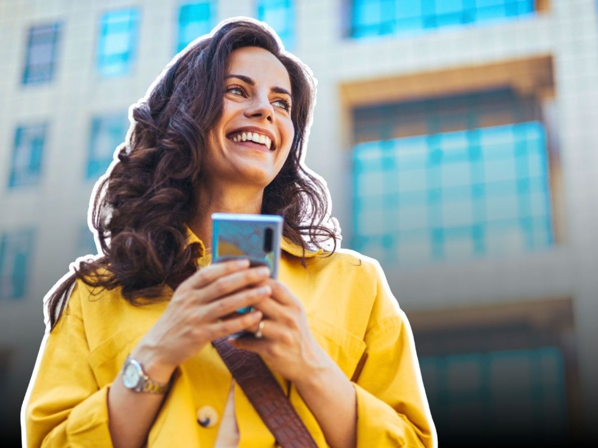 Lächelnde Frau mit Smartphone in ihrer Hand.