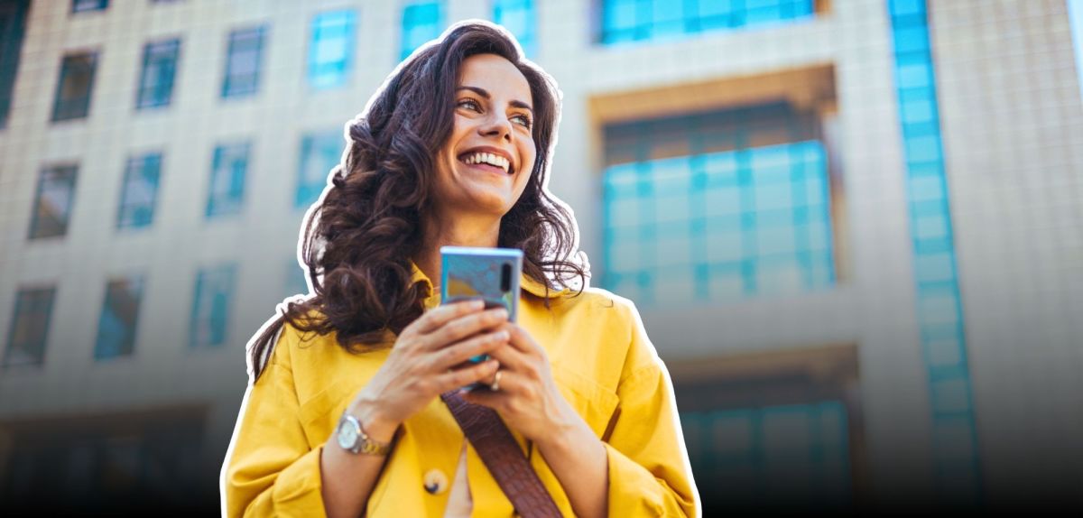 Lächelnde Frau mit Smartphone in ihrer Hand.