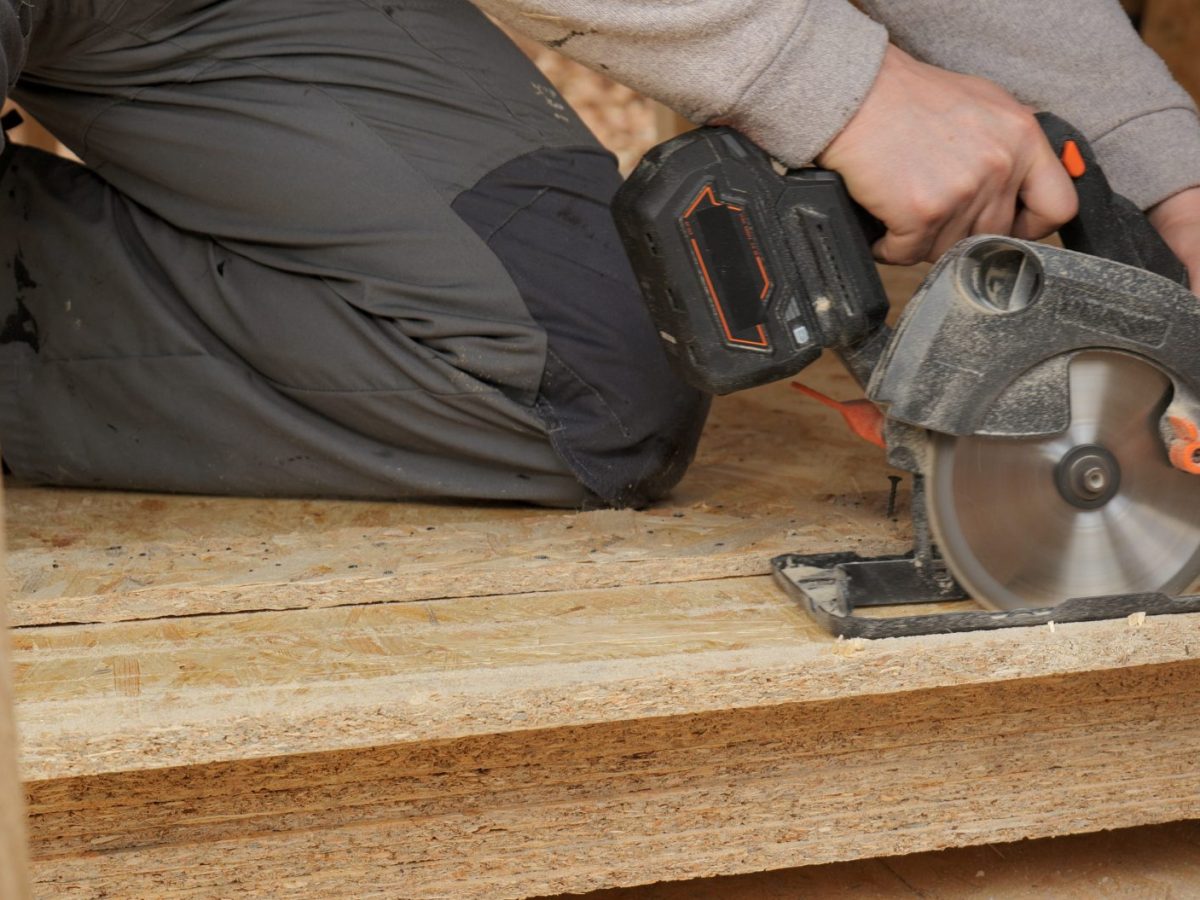 Person bearbeitet Holz mit einer Akku-Handkreissäge.