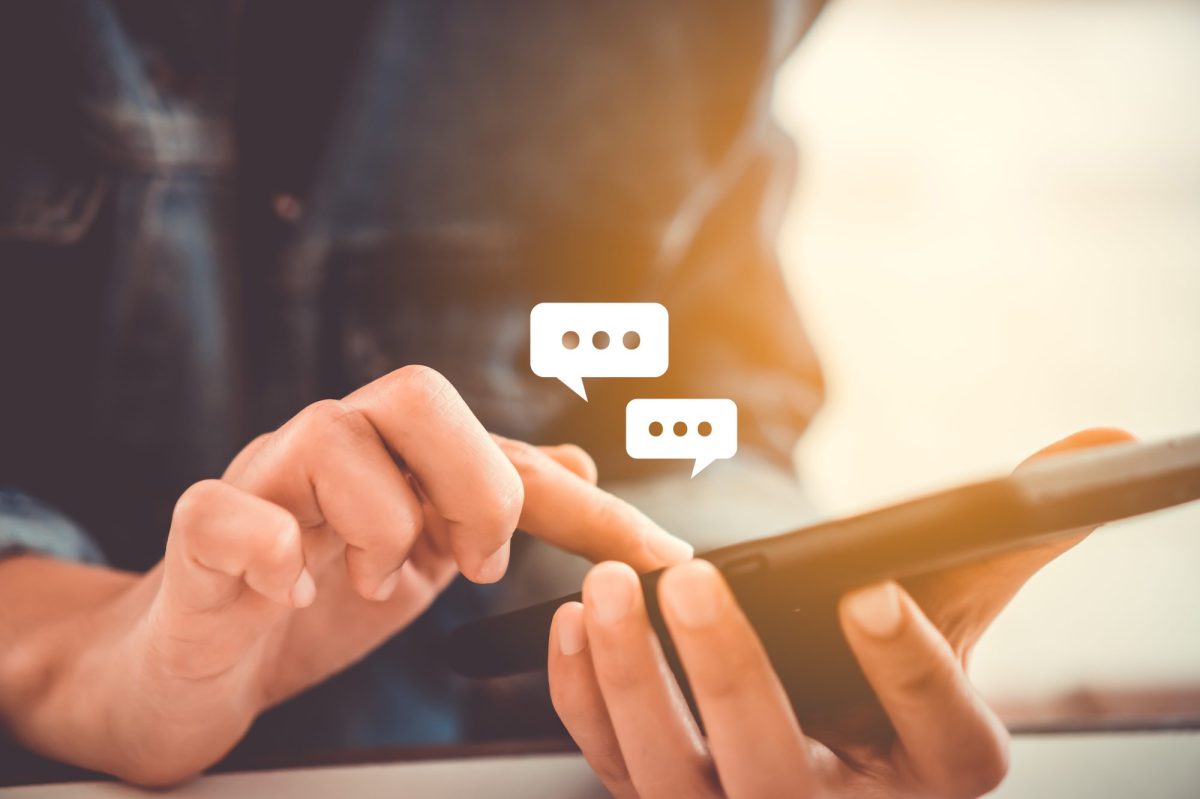 Eine Person hält ein Smartphone in der Hand. Darüber erscheinen Sprechblasen.
