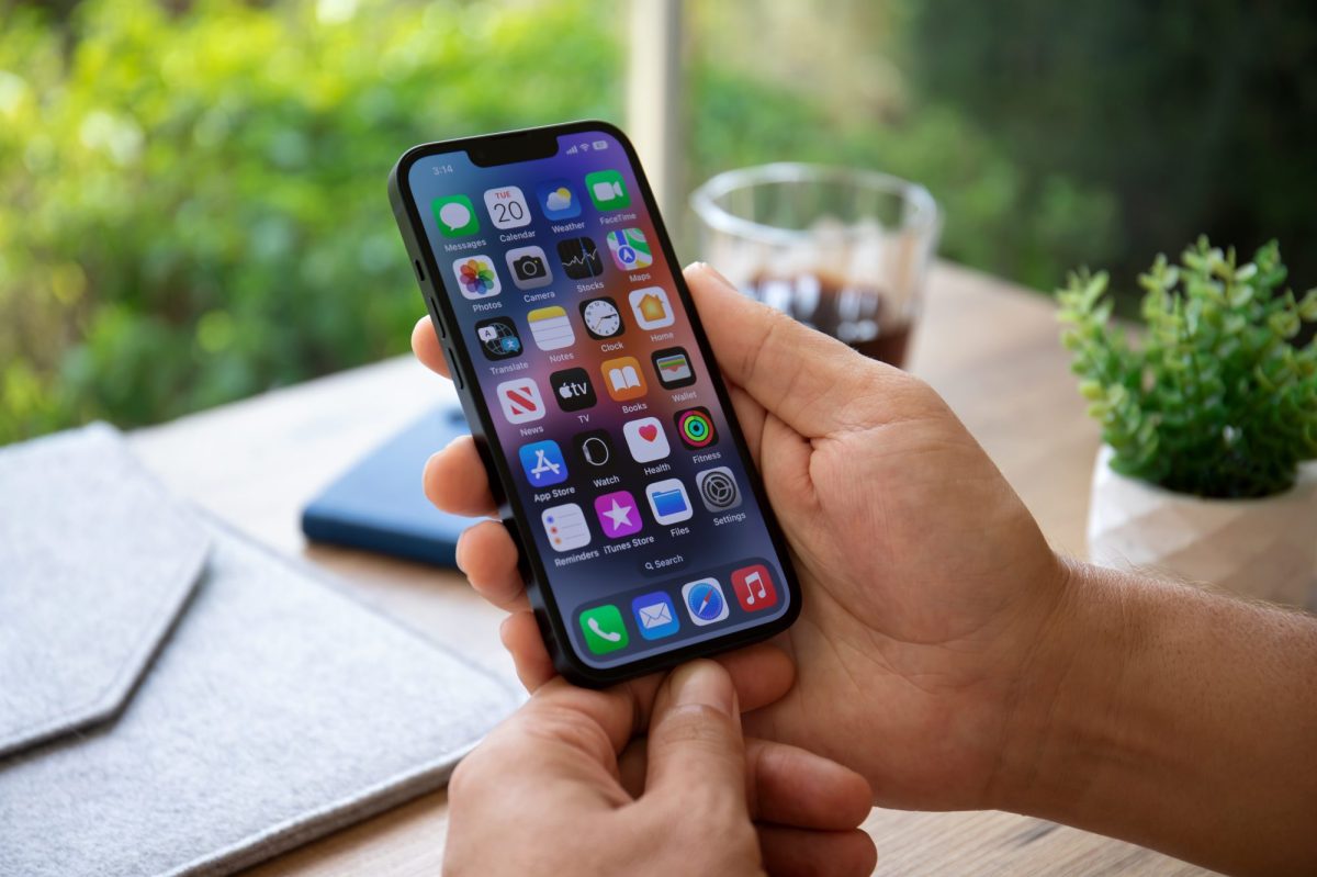 Person hält ein eingeschaltetes iPhone in der Hand.