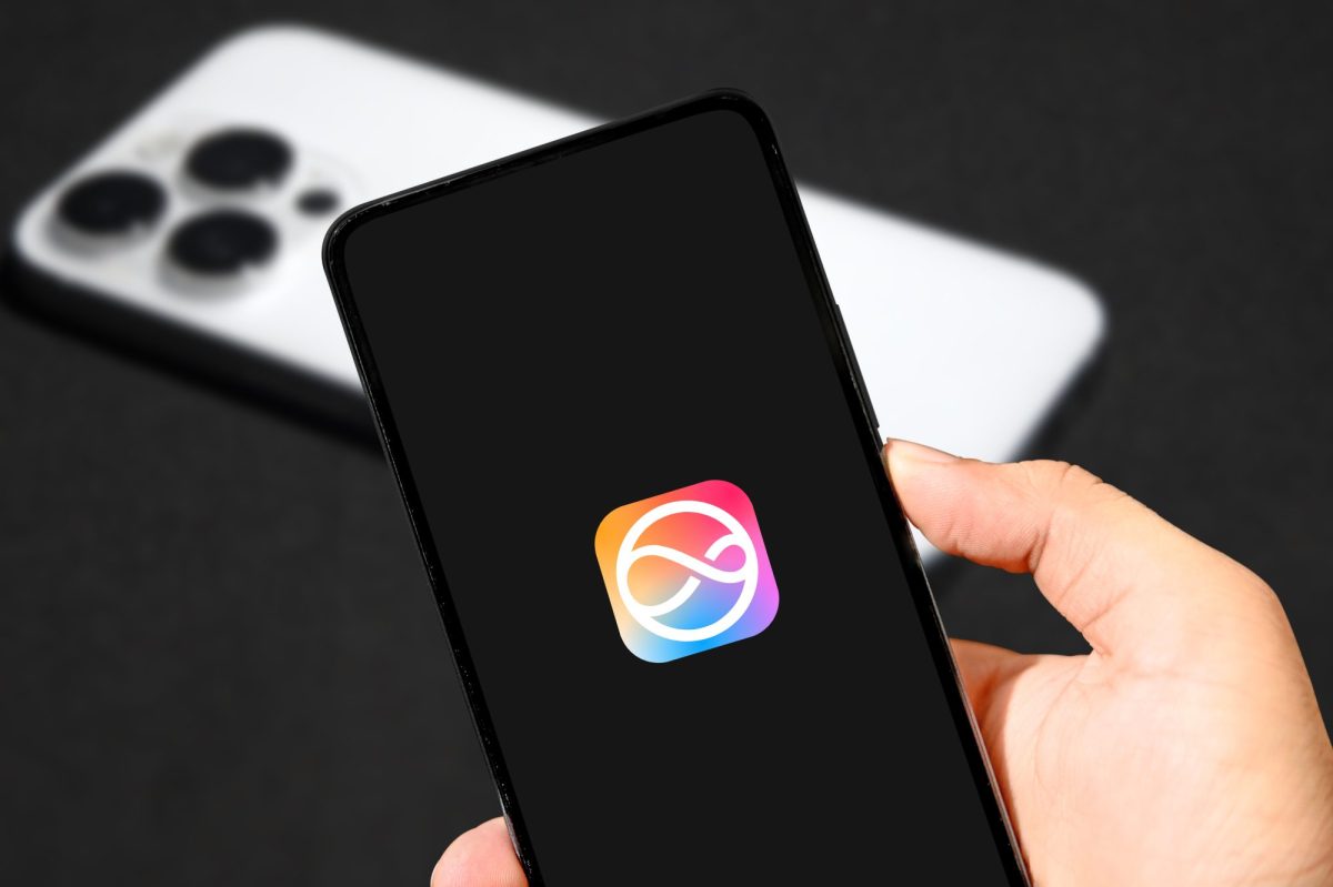 Person hält ein iPhone in der Hand, auf dem Display ist das iOS-Logo zu sehen.