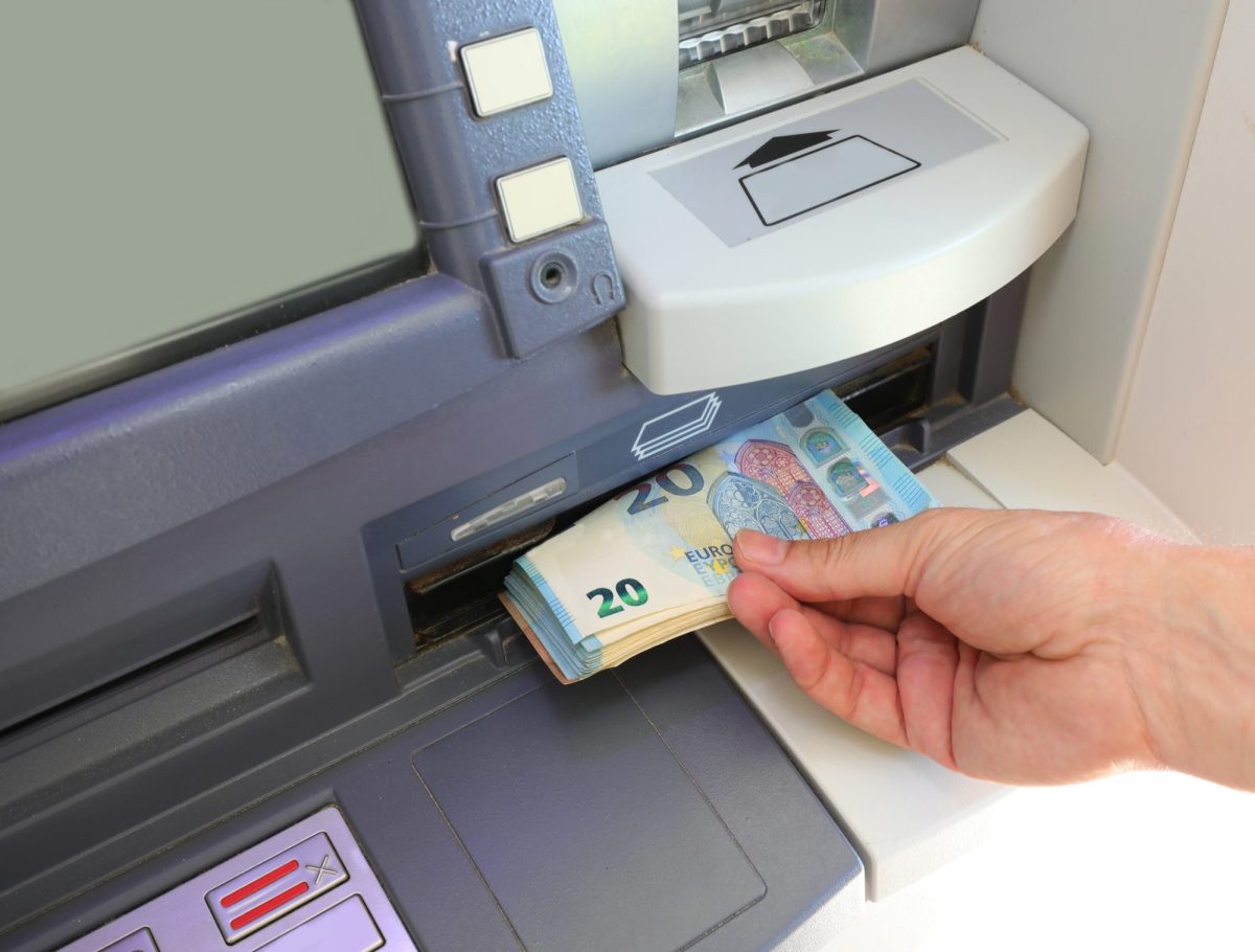 Person hebt Bargeld an einem Bankautomaten ab.