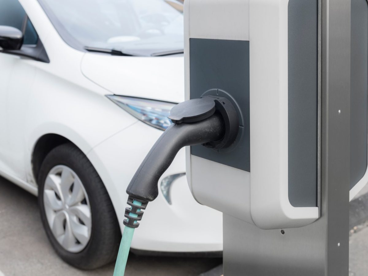 Ladesäule für Elektroautos. Im Hintergrund steht ein geparktes Auto.