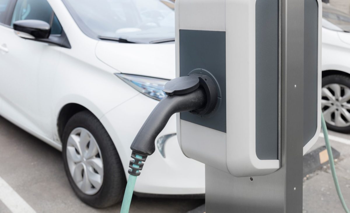 Ladesäule für Elektroautos. Im Hintergrund steht ein geparktes Auto.