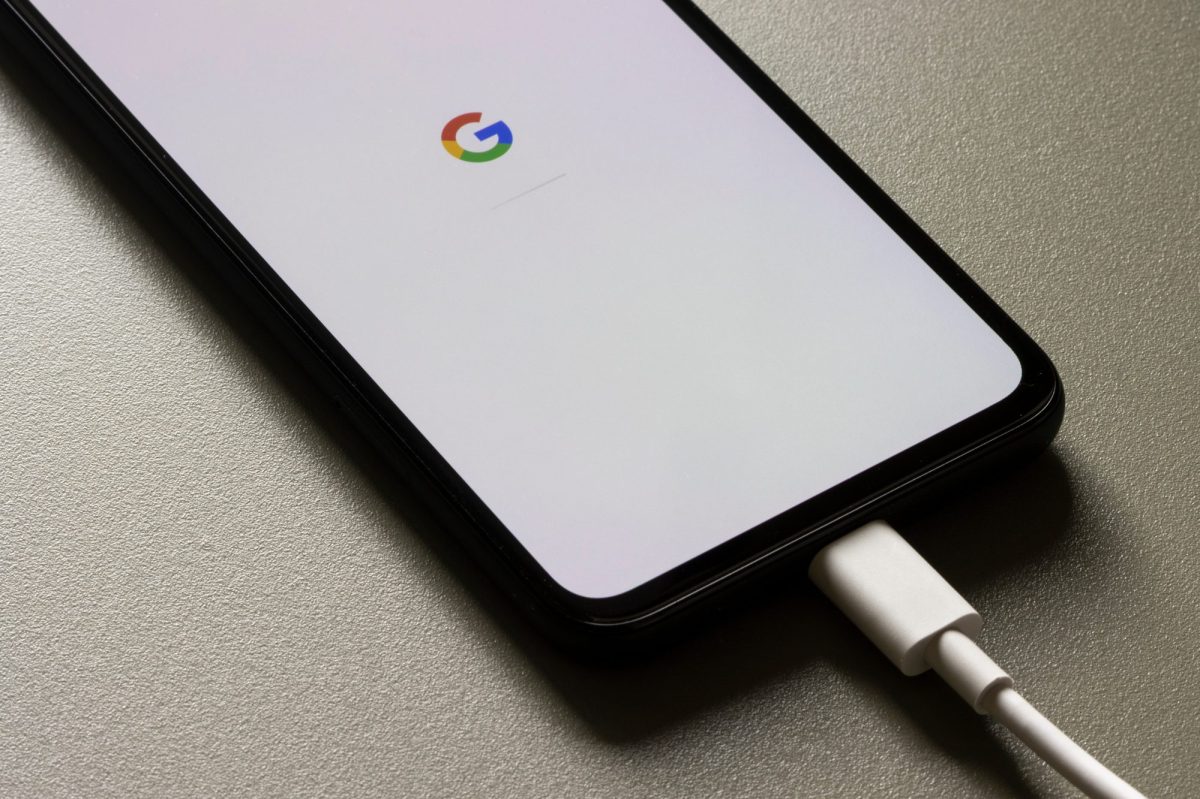 Ein Smartphone ist an ein Ladekabel angeschlossen, auf dessen Display wird das Google-Logo angezeigt.