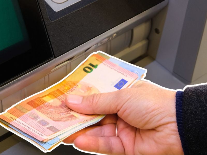Person hebt an einem Automaten Geld ab.