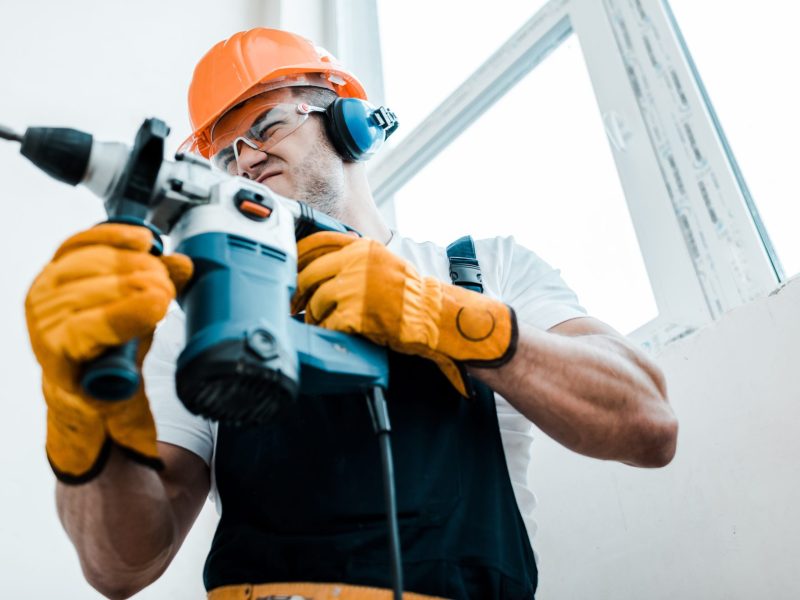 Mann benutzt einen Makita-Bohrhammer.