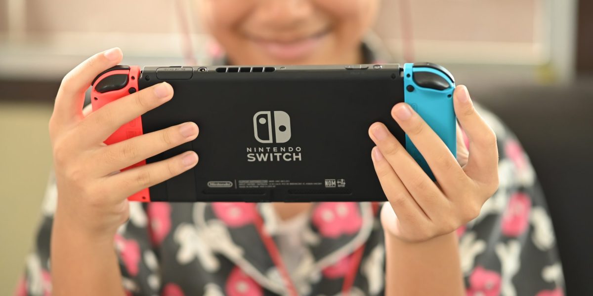 Kind hält Nintendo Switch in der Hand.