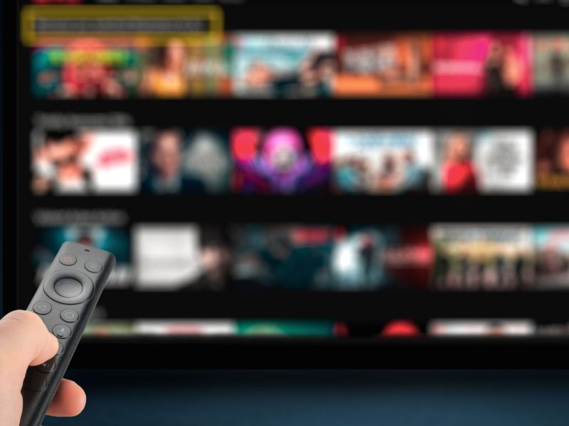 Person mit Fernbedienung vor einem Fernseher