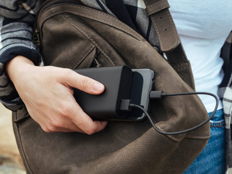 Person hält ein Handy und eine Powerbank in der Hand.