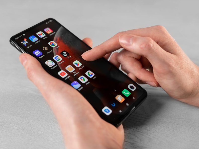 Person hält ein Android-Handy in der Hand, auf dem mehrere Apps angezeigt werden.