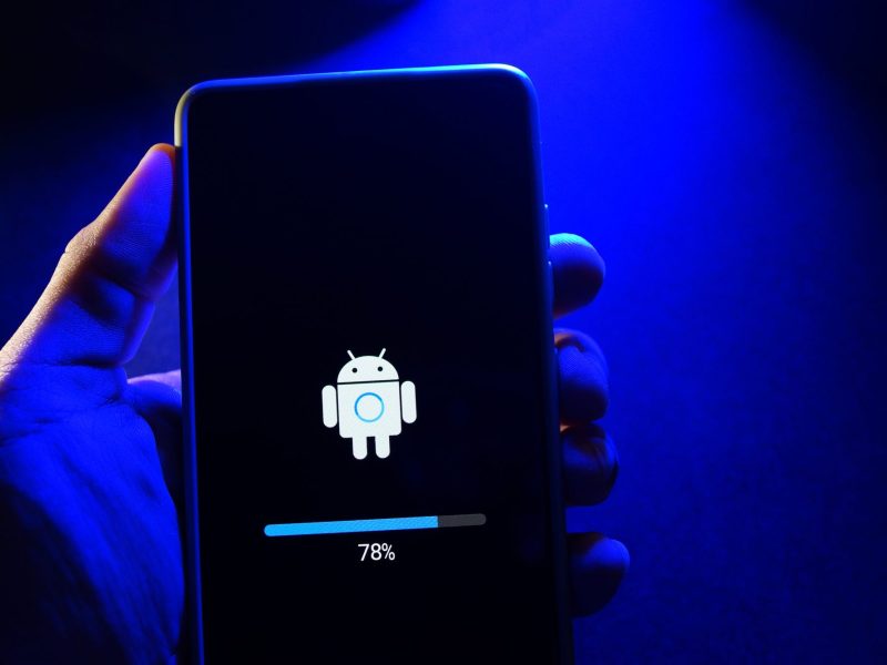 Person hält ein Handy in der Hand, auf dem ein neues Android-Update geladen wird.