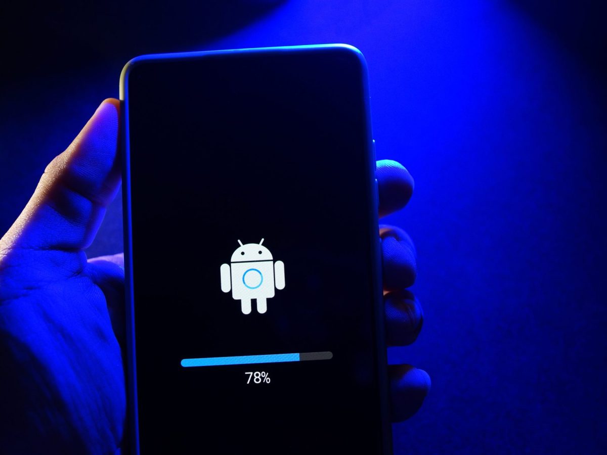 Person hält ein Handy in der Hand, auf dem ein neues Android-Update geladen wird.