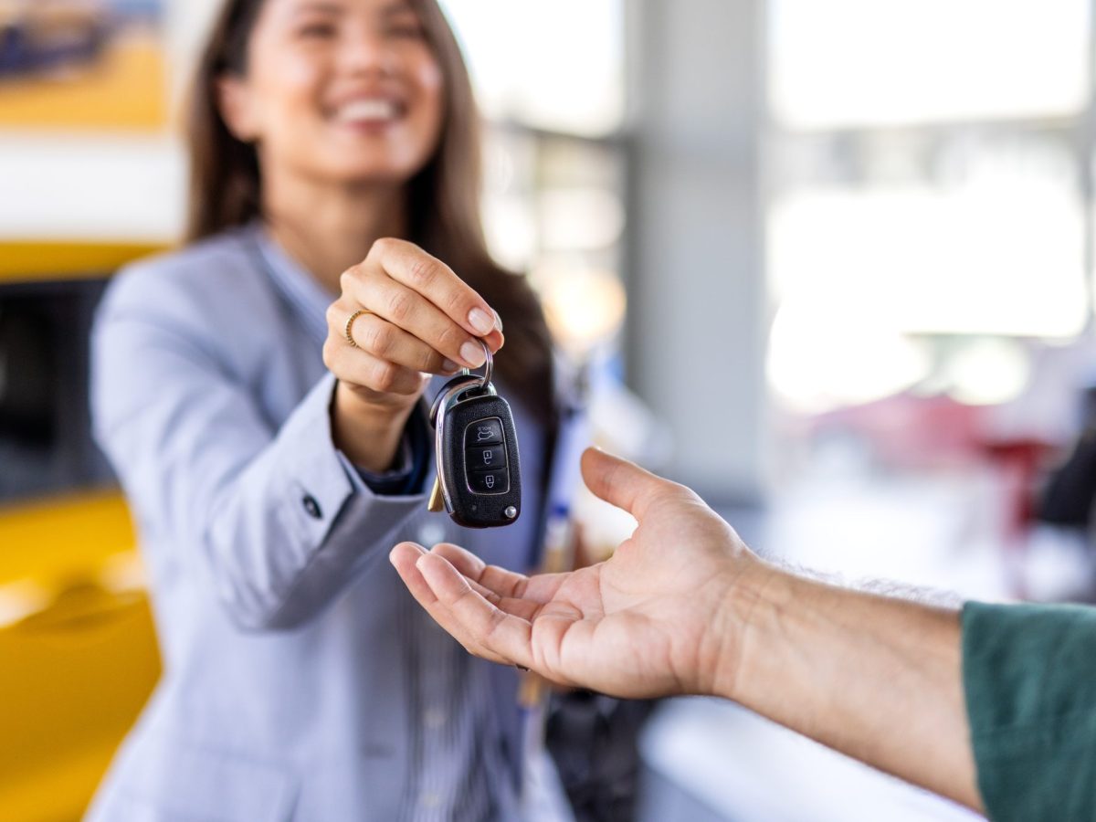 Frau übergibt Autoschlüssel an eine weitere Person.