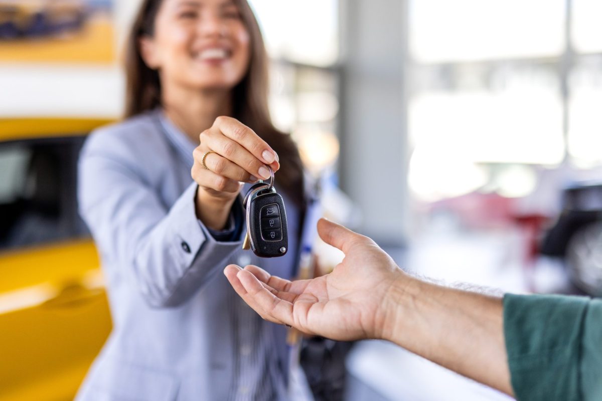 Frau übergibt Autoschlüssel an eine weitere Person.