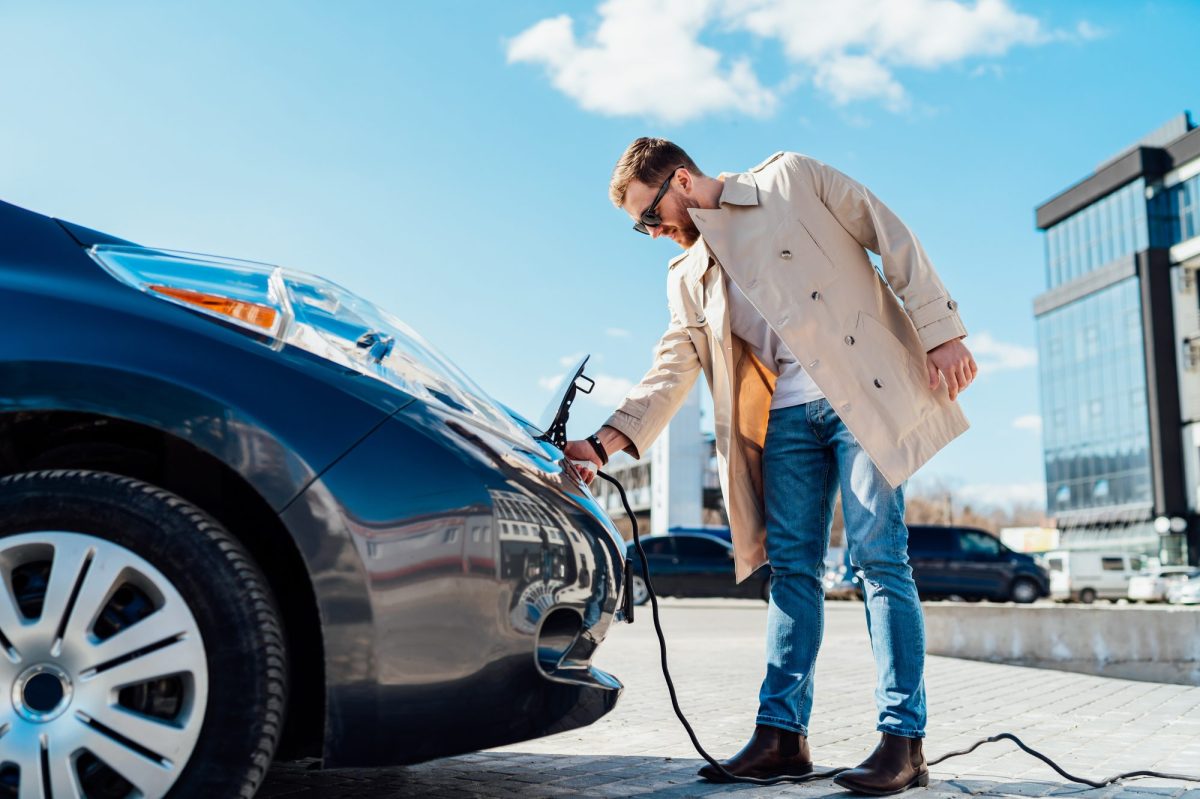 Ein Mann lädt ein Elektroauto.