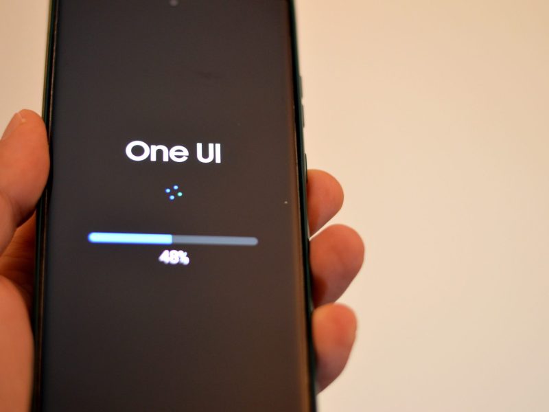 Person hält ein Samsung Galaxy-Handy in der Hand, auf dem eine neue One UI-Version geladen wird. (Symbolbild)