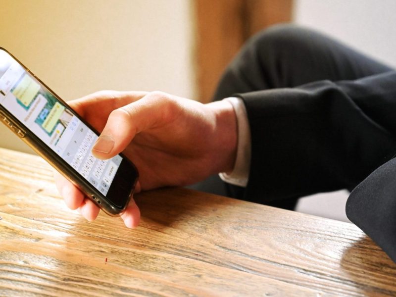 Mann hält Smartphone, auf dem WhatsApp geöffnet ist.