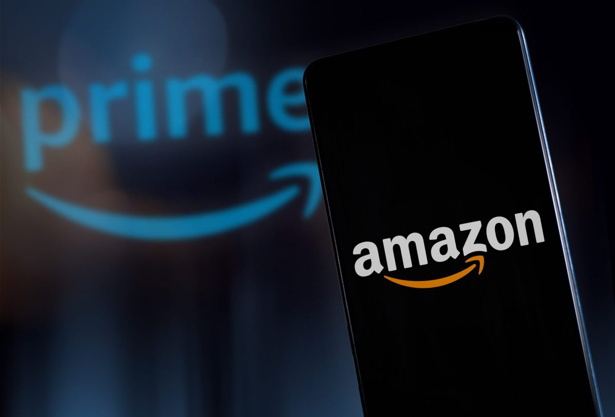 Auf einem Handy-Display ist das Amazon-Logo zu sehen. Im Hintergrund steht das Prime-Logo.