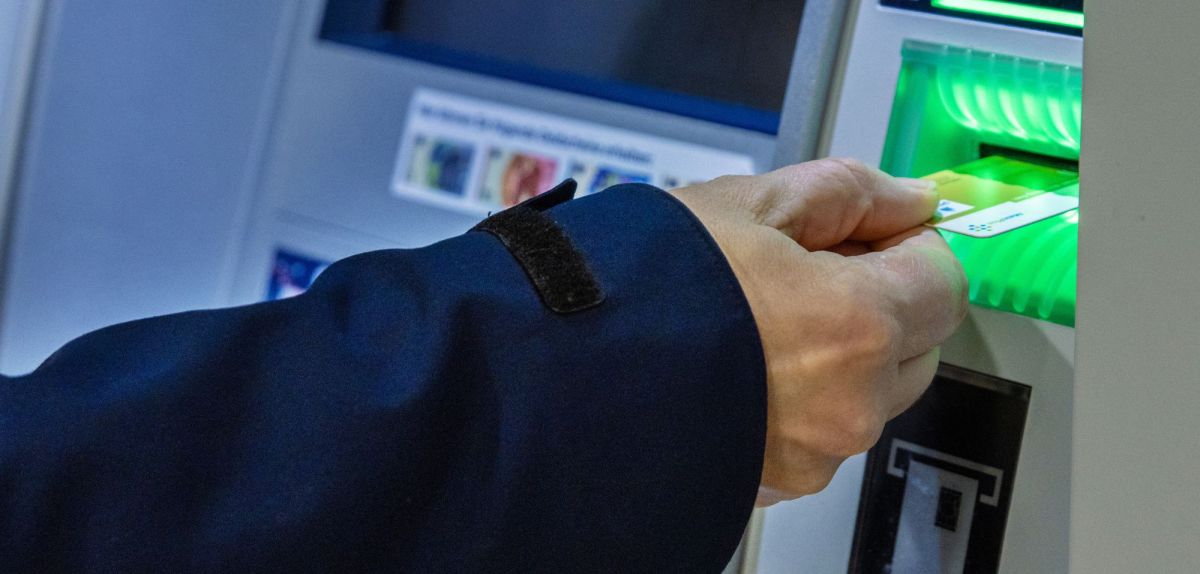 Person gibt eine Bankkarte in einen Bankautomaten ein.