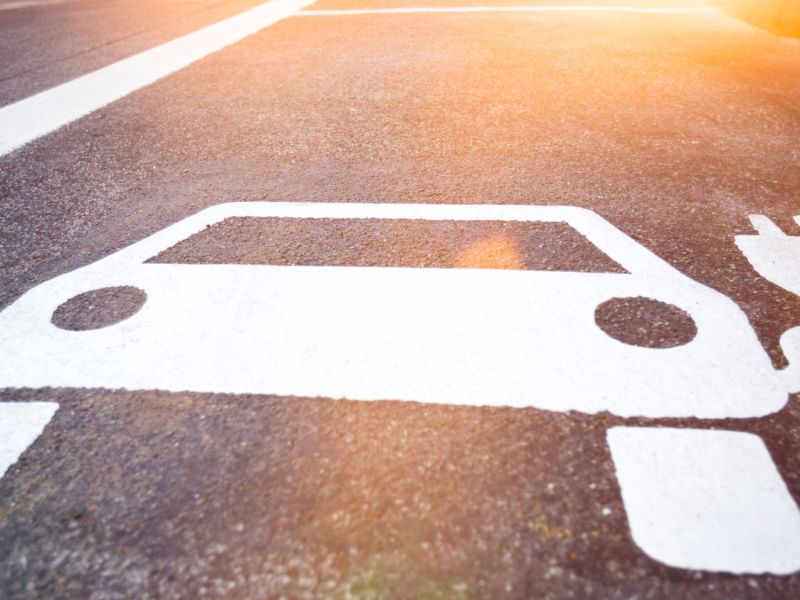 Symbol eines Elektroautos auf Asphalt.