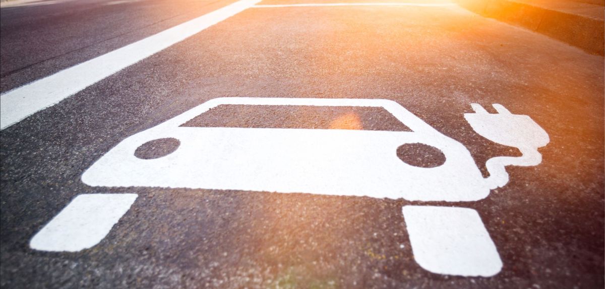 Symbol eines Elektroautos auf Asphalt.