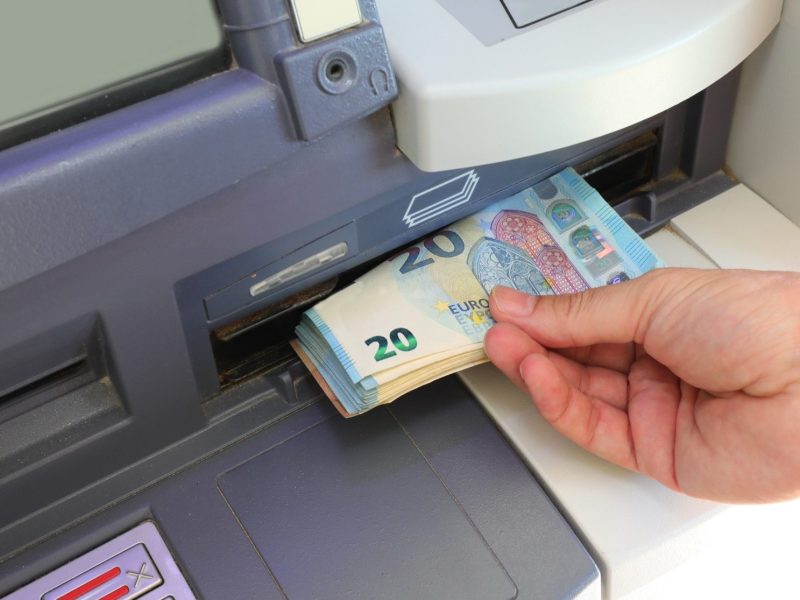 Person hebt Geld am Geldautomaten ab