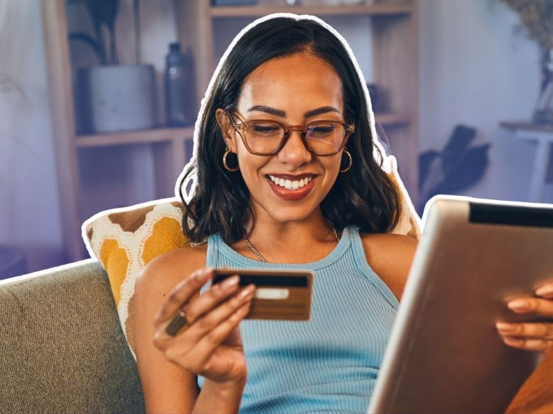 Frau mit Kreditkarte und Tablet auf einem Sofa