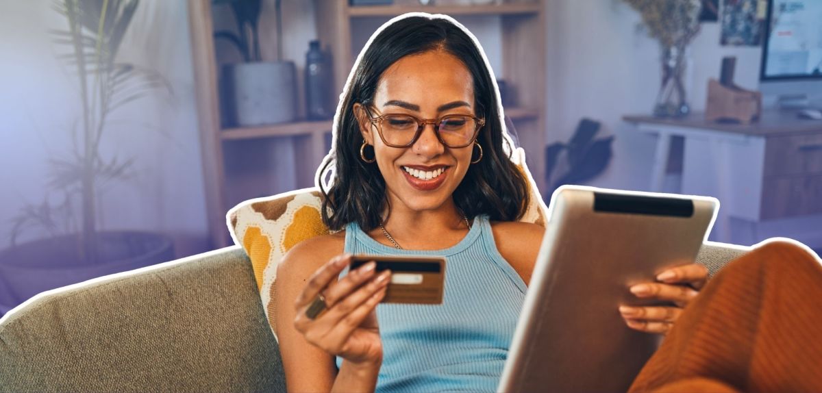 Frau mit Kreditkarte und Tablet auf einem Sofa