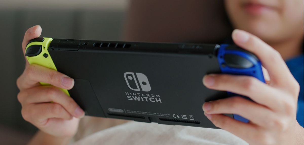 Kind hält Nintendo Switch in der Hand.