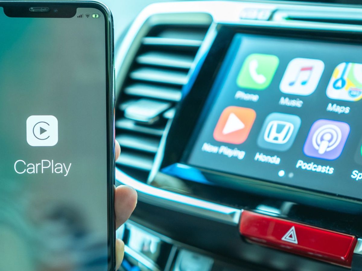 Person sitzt in einem Auto und bedient Apple Carplay an einem iPhone.