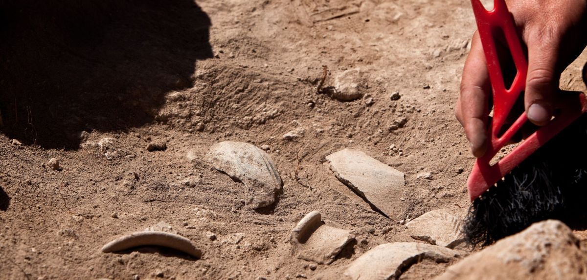 Person arbeitet mit Pinsel an einem archäologischen Fund.