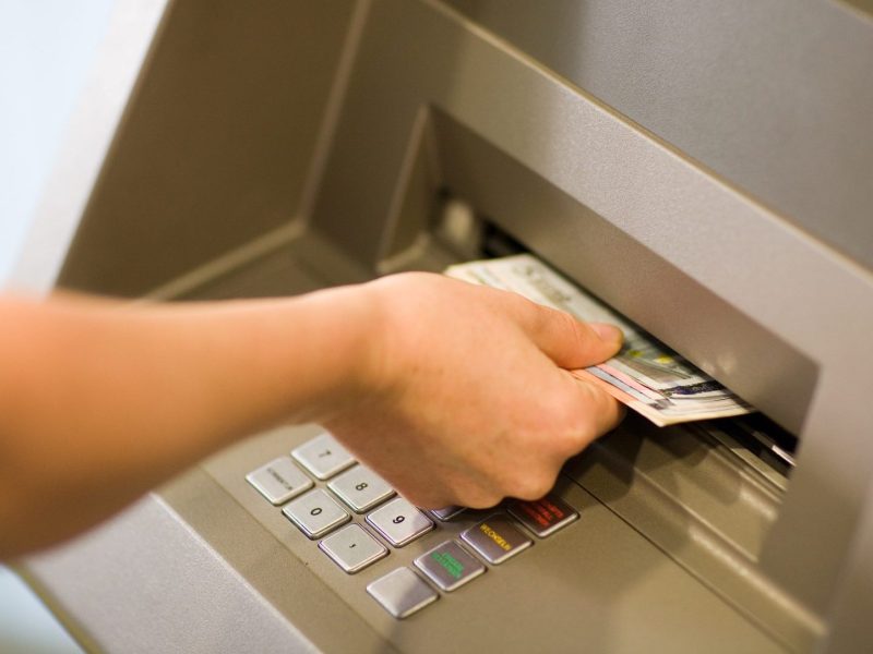 Person hebt Geld vom Automaten ab.