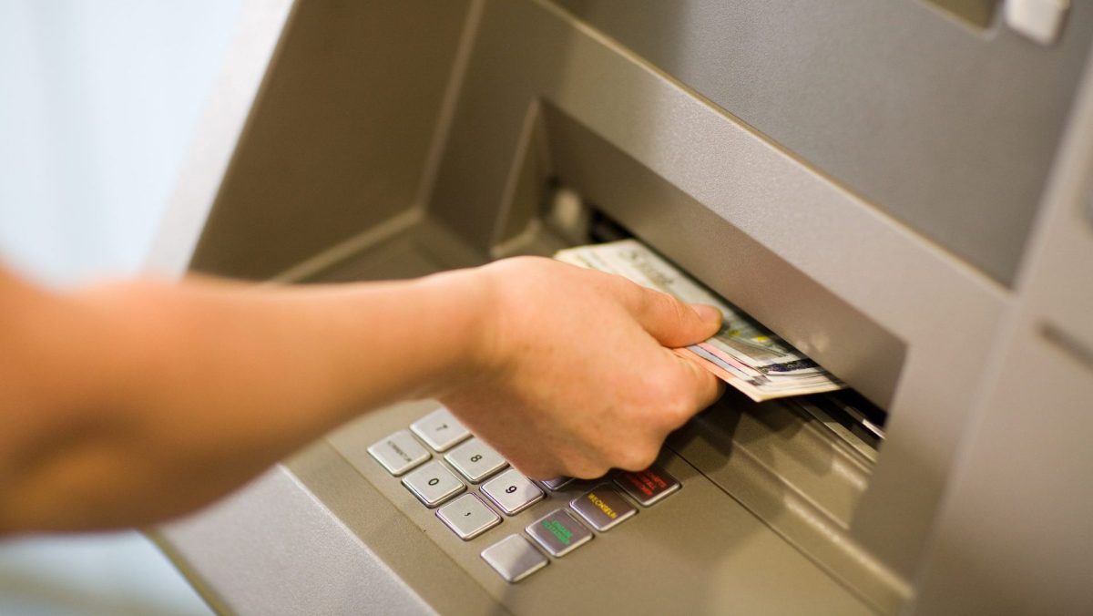 Person hebt Geld vom Automaten ab.