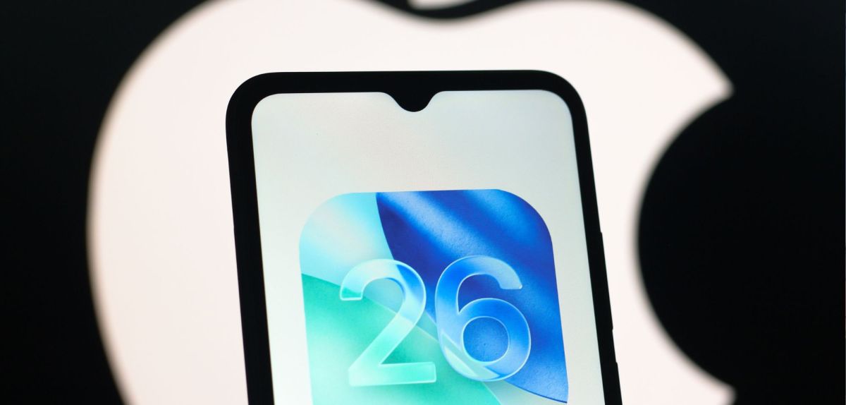 iOS 26-Logo auf einem Handy-Display. Im Hintergrund ist das Apple-Logo.