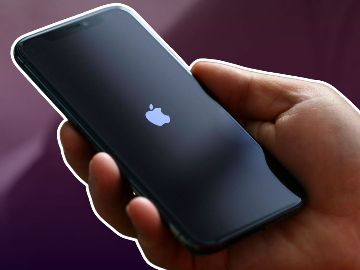 Hand hält ein iPhone mit Apple-Logo auf dem Display.