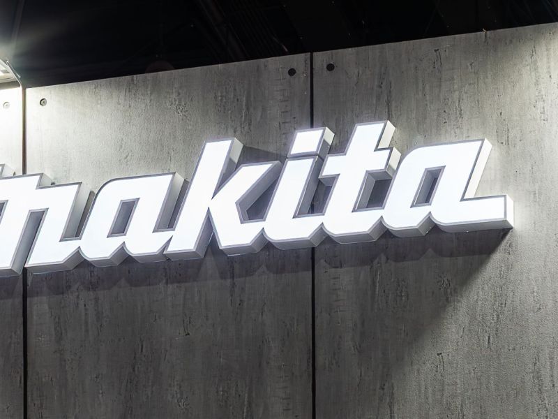 Makita-Logo an einer Wand mit Holzoptik.