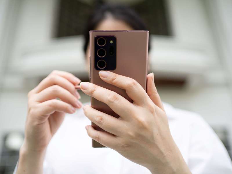 Person hält Smartphone in der Hand und tippt auf das Display des Handys.