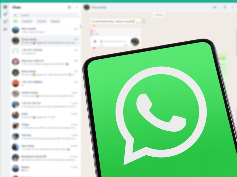 WhatsApp-Logo mit Chats im Hintergrund