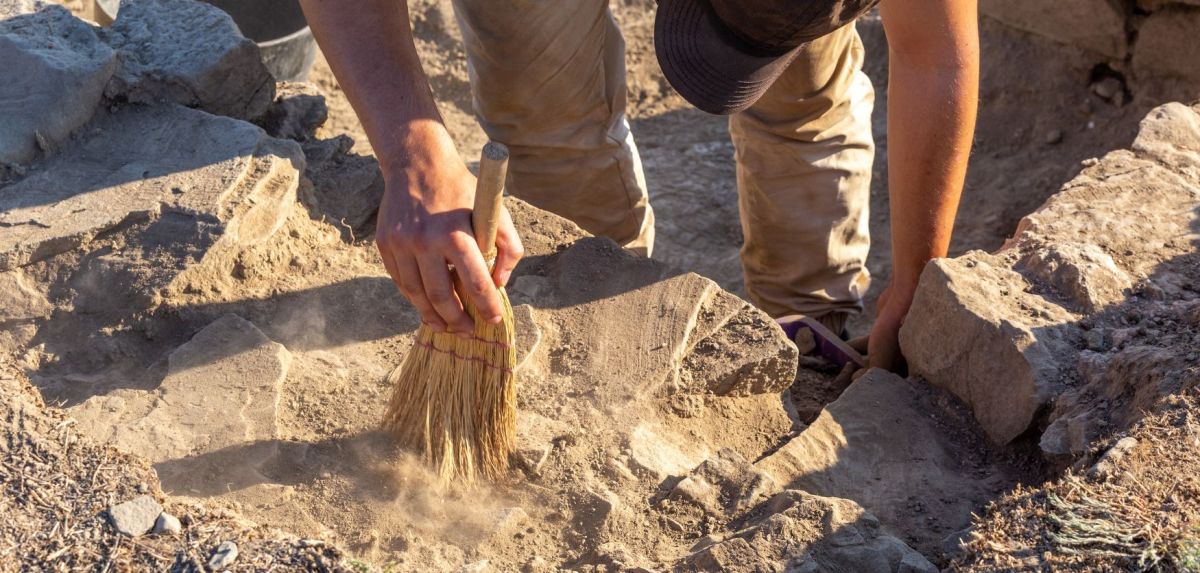 Person untersucht einen archäologischen Fund.