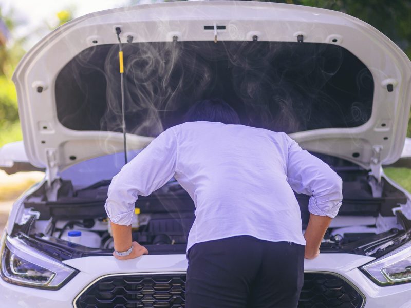 Mann steht vor kaputtem Automotor.
